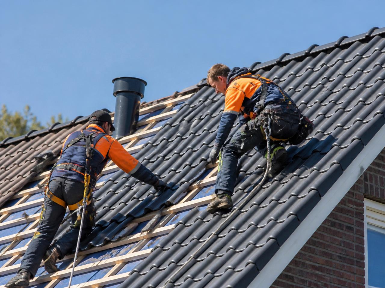 Dakwerkers inspecteren het dakvlak en de aansluitingen van een woning